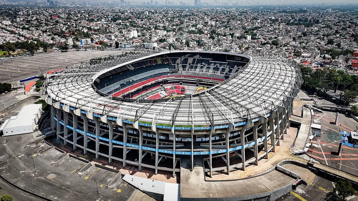 Estadio Azteca packed with fans on a clear afternoon, showing the steep upper deck and the Mexico City basin behind it