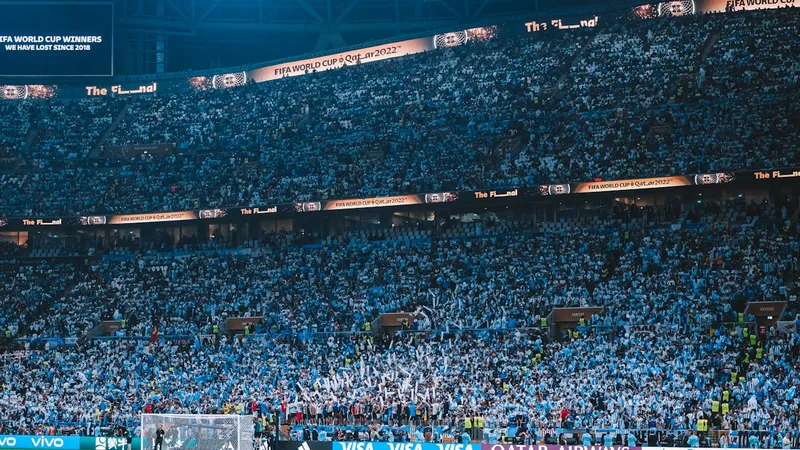 Packed stadium crowd watching a soccer match under bright floodlights