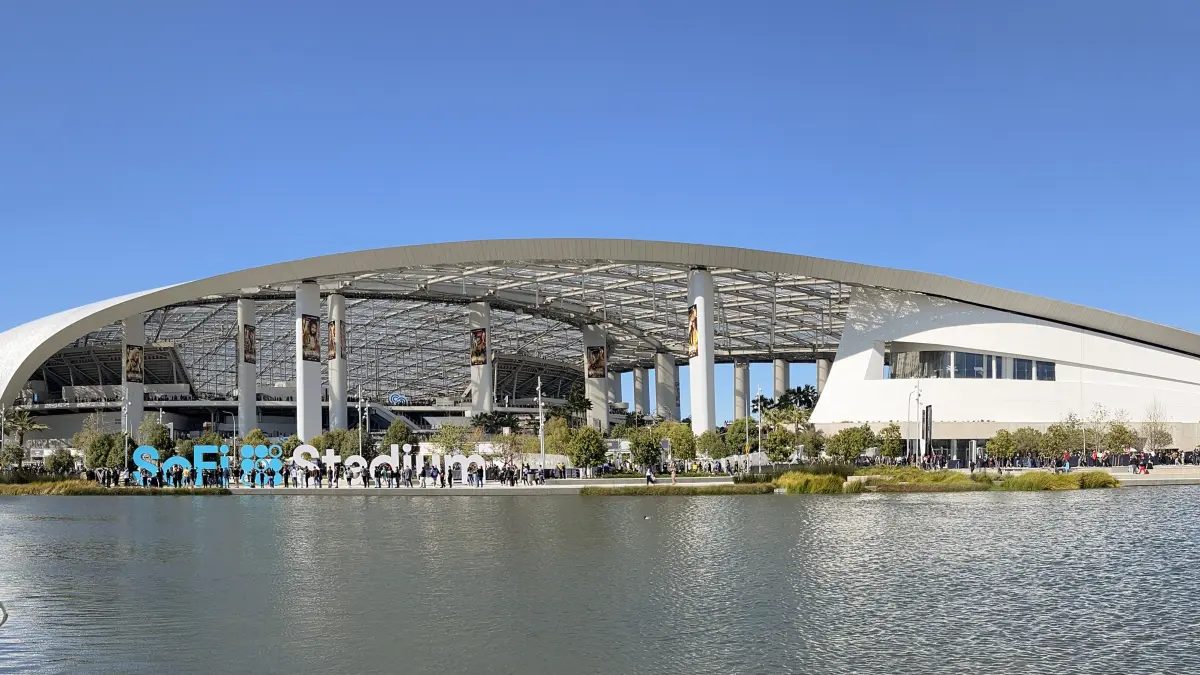 SoFi Stadium in Inglewood, the most expensive stadium ever built, seen across its lake with the translucent canopy roof