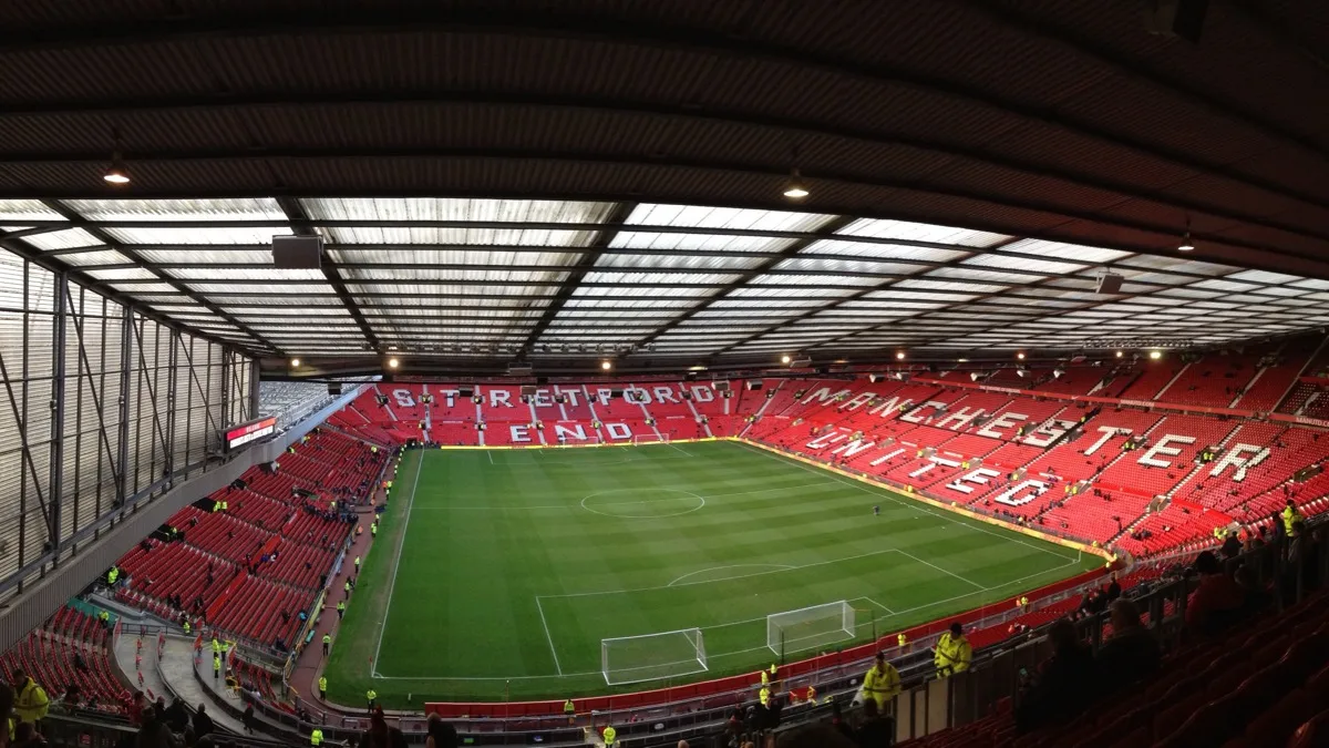 The interior bowl of Old Trafford before a match, the Stretford End and Manchester United picked out in white seats across the red tiers