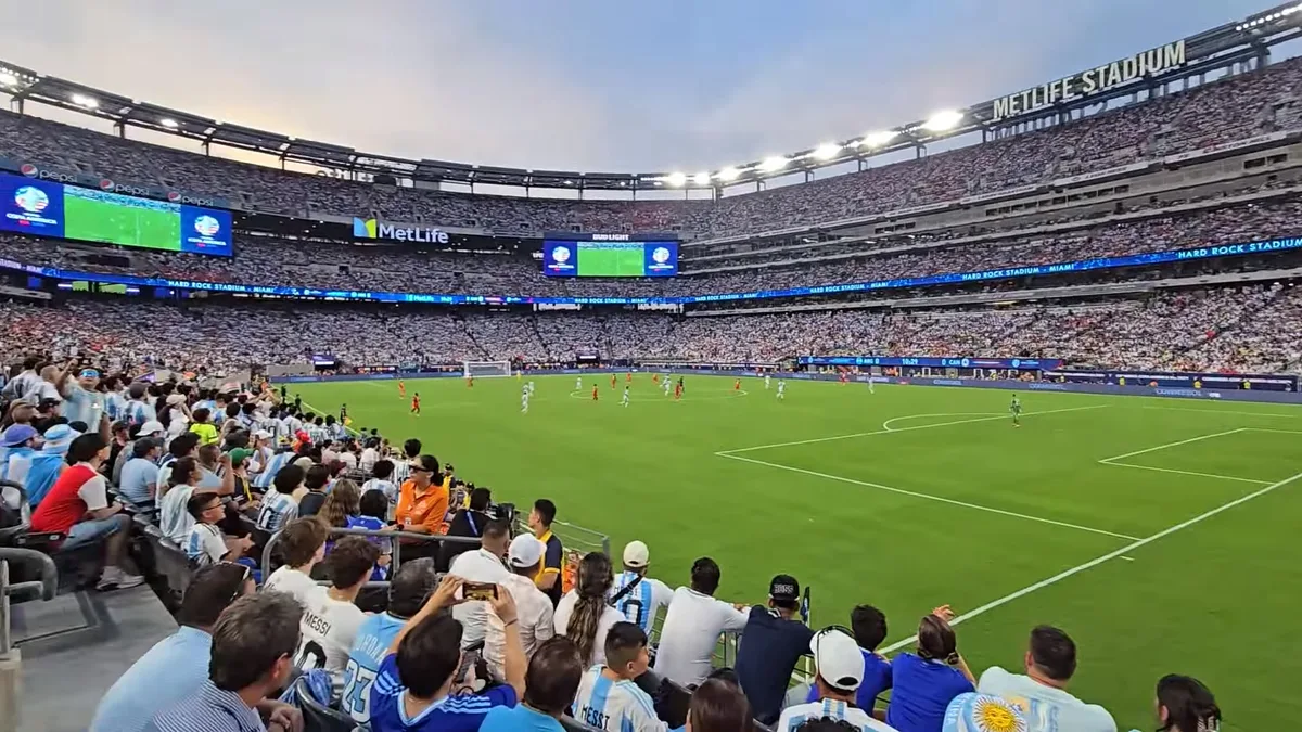 Fan-view interior shot of MetLife Stadium during the Argentina vs Canada Copa América 2024 semifinal, showing the packed lower bowl, the soccer pitch in play, and the MetLife Stadium signage on the scoreboard