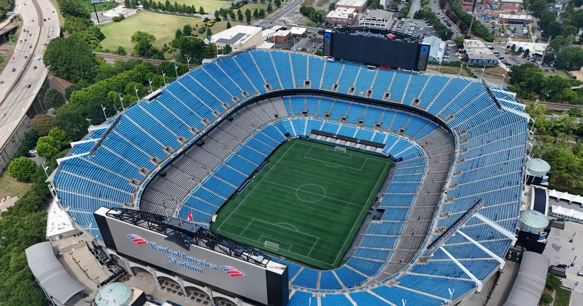 Aerial view of Bank of America Stadium, its blue-seated bowl surrounded by uptown Charlotte streets and the interstate
