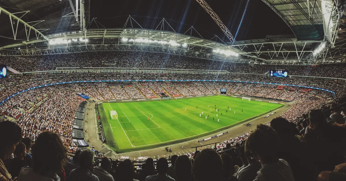 Wembley Stadium at night, a full crowd under floodlights with the arch above the roof