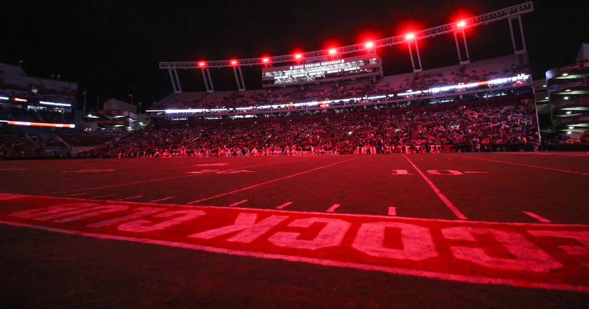 Williams-Brice Stadium at night, the bowl lit red with a full crowd under the floodlights