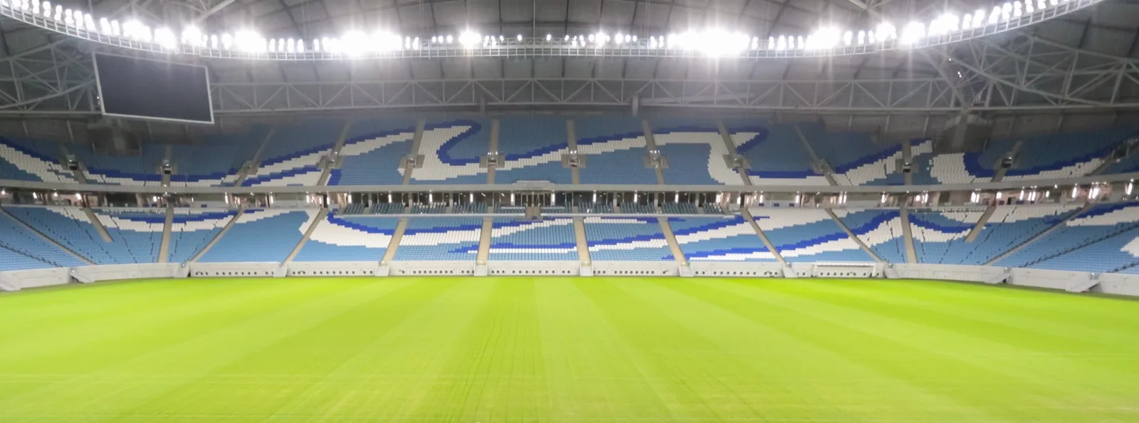 The empty Al Janoub Stadium bowl with its blue-and-white wave-patterned seating