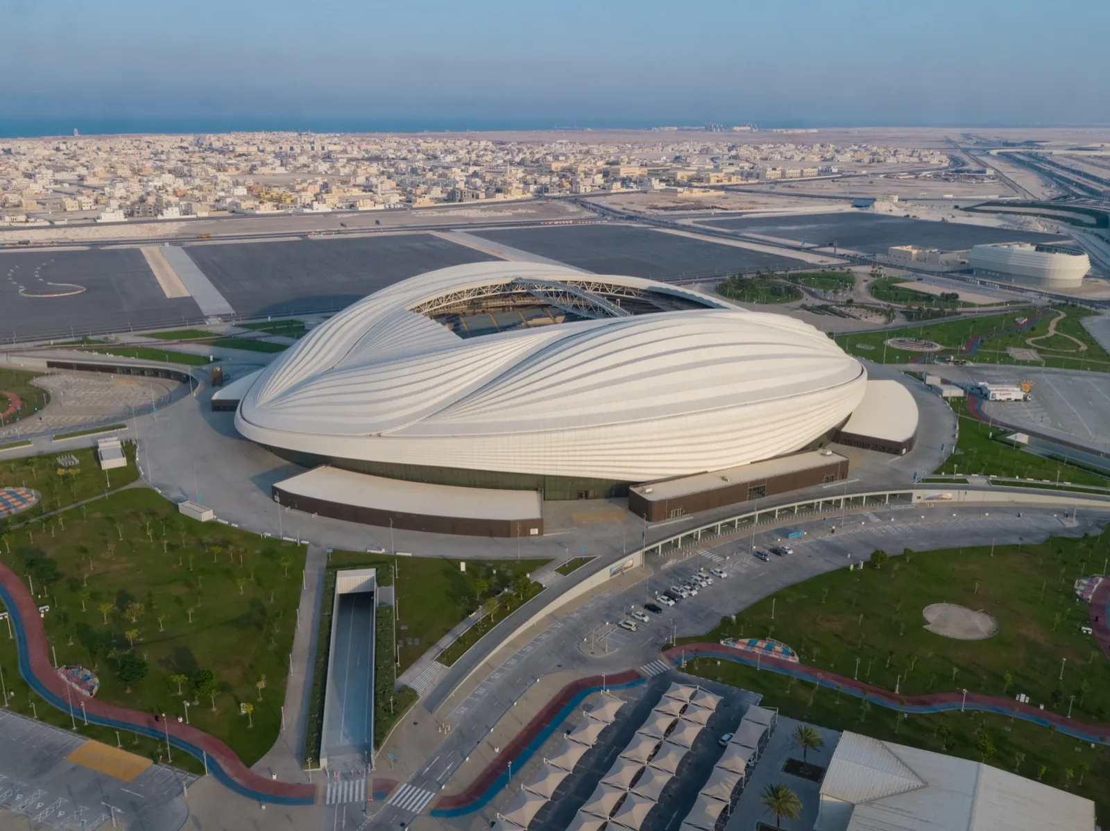 Al Janoub Stadium's curving sail-shaped roof and white facade in Al Wakrah